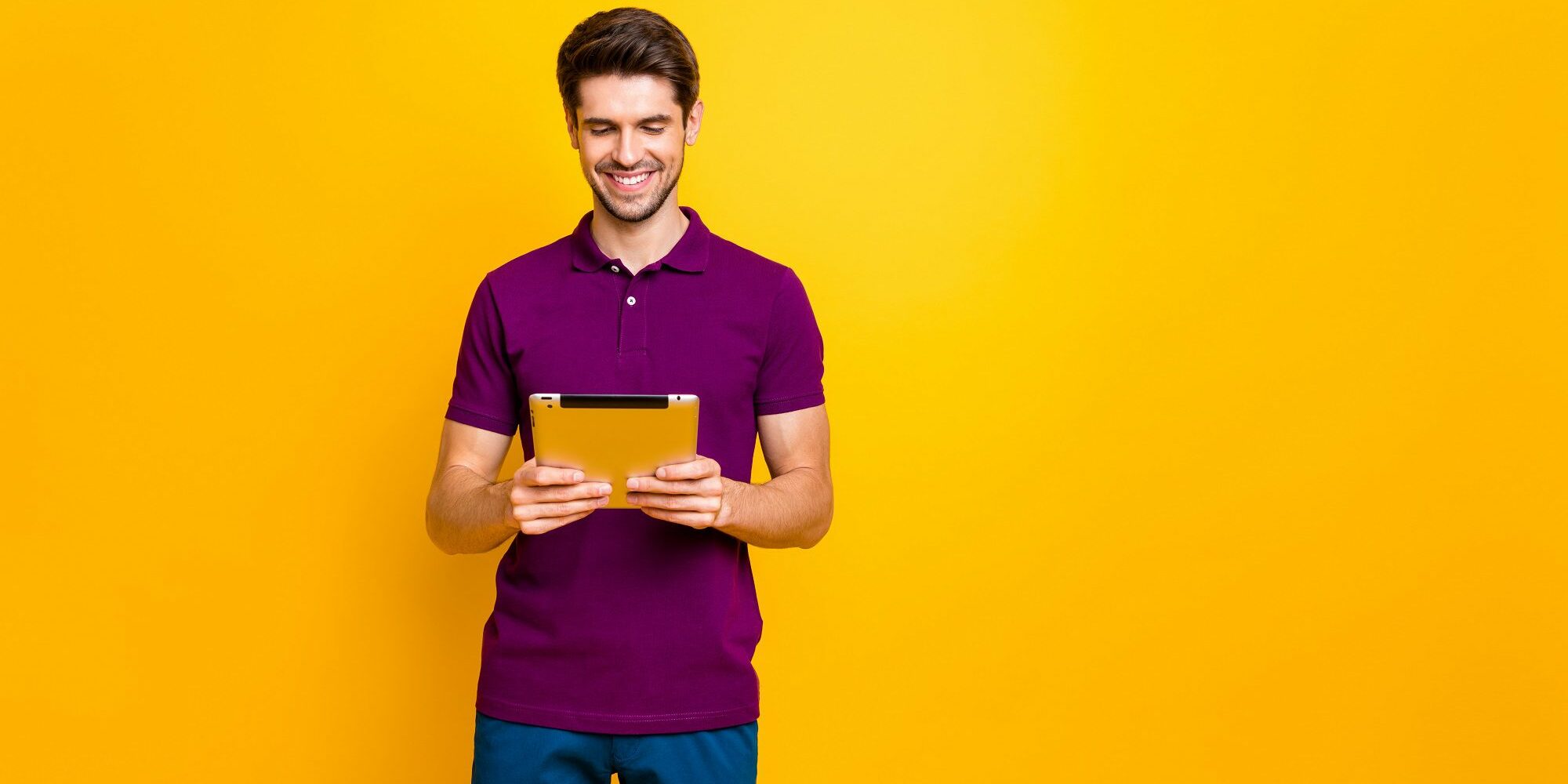 Portrait of his he nice attractive focused cheerful cheery guy using, reading ebook isolated over bright vivid shine vibrant yellow color background